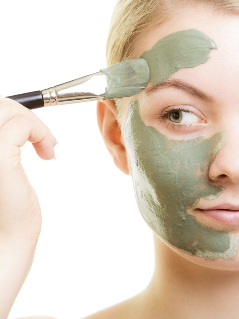 Woman applying green face mask