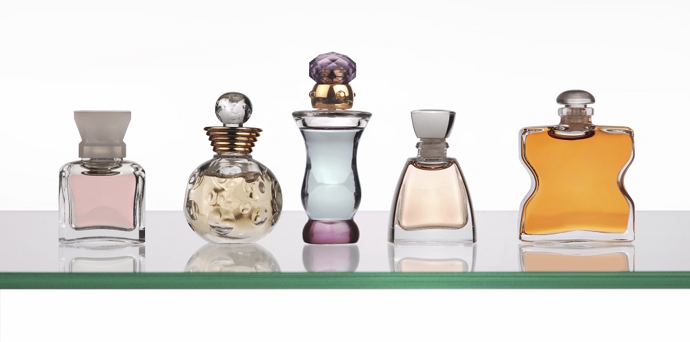 perfume bottles lined up on glass shelf