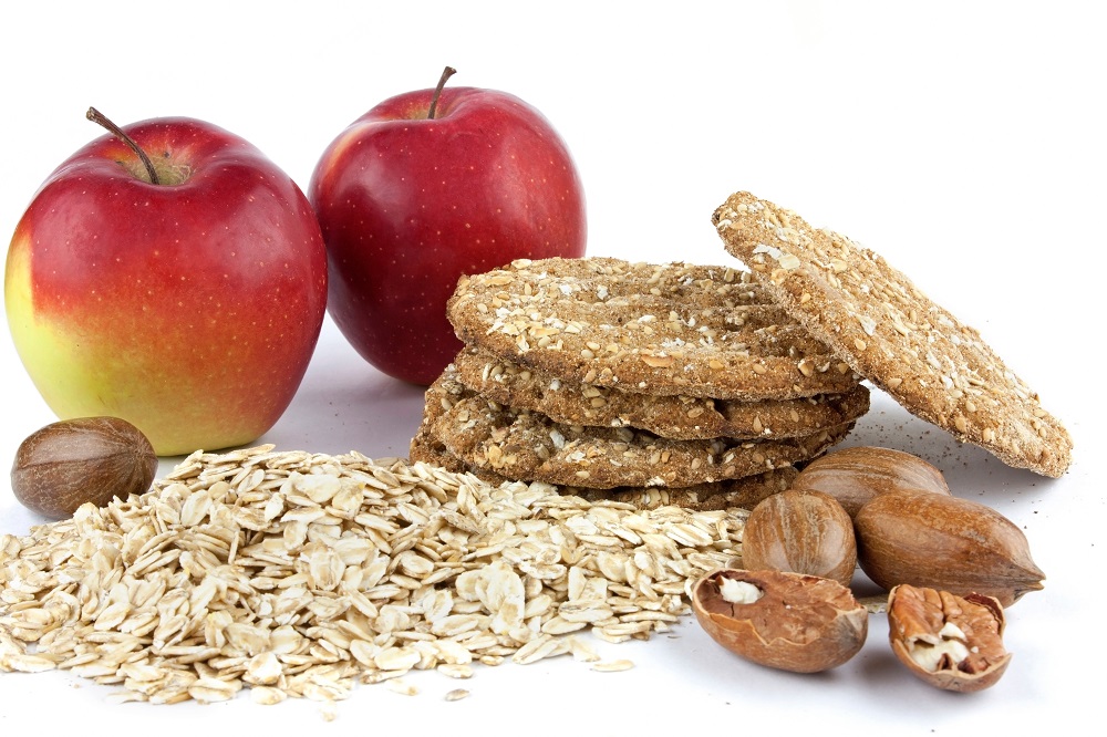 Red apples with oatmeal, integral biscuits and pecan nuts on white