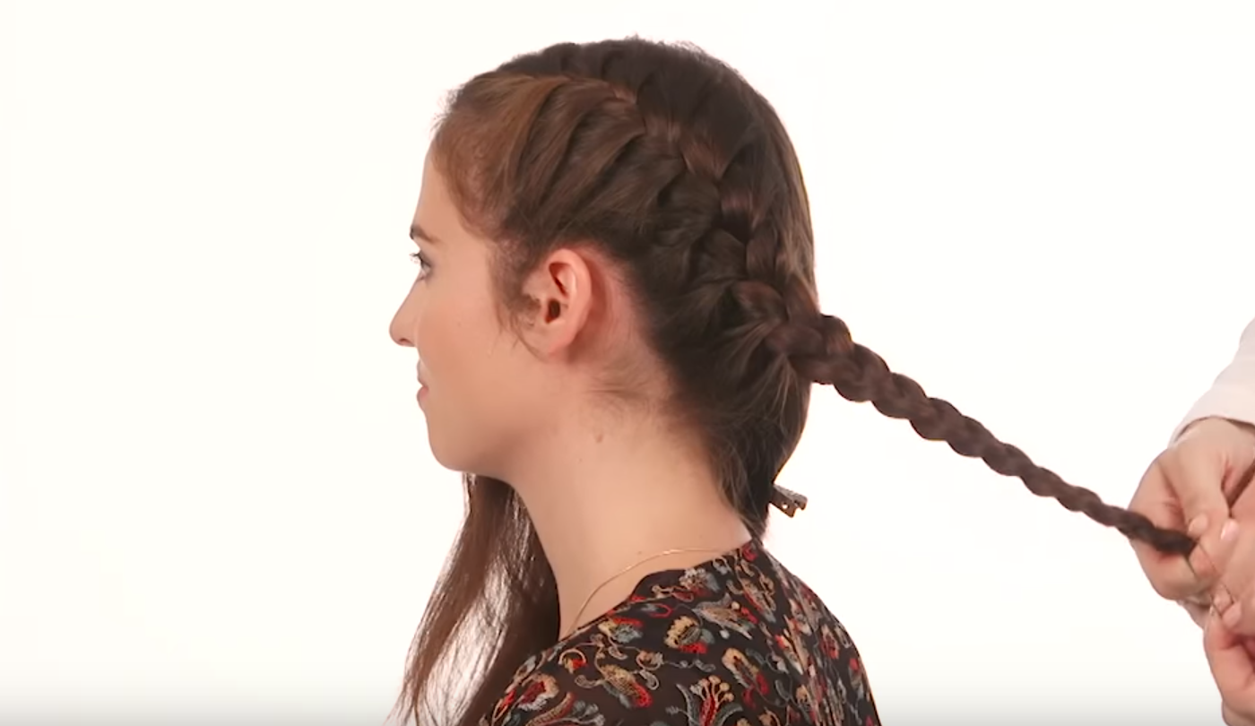 Hairstylist creating French braid on model's hair