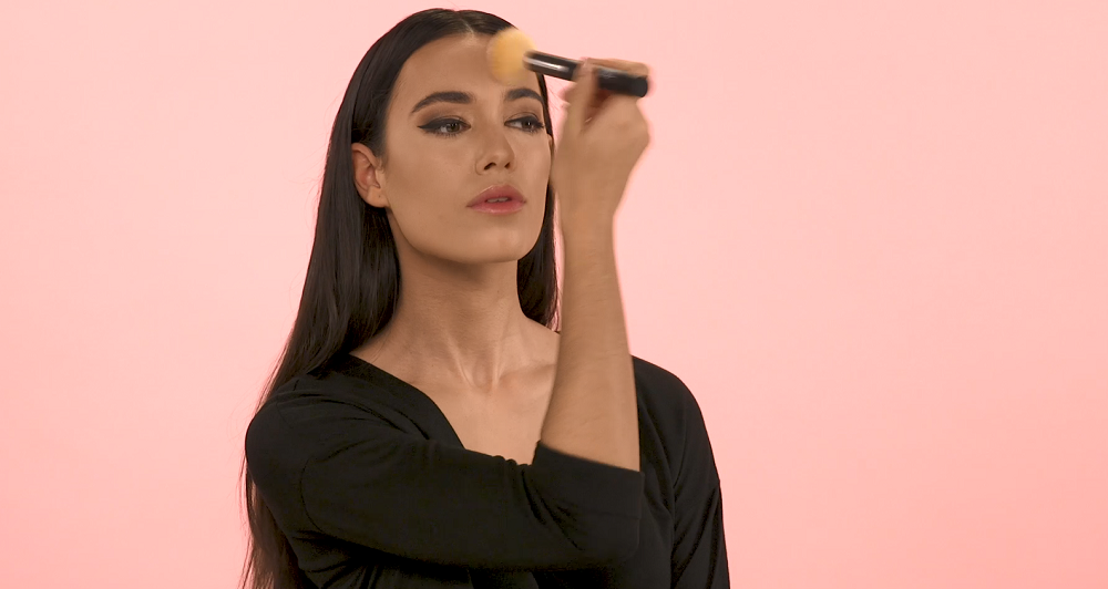 Woman applying setting powder to face with brush