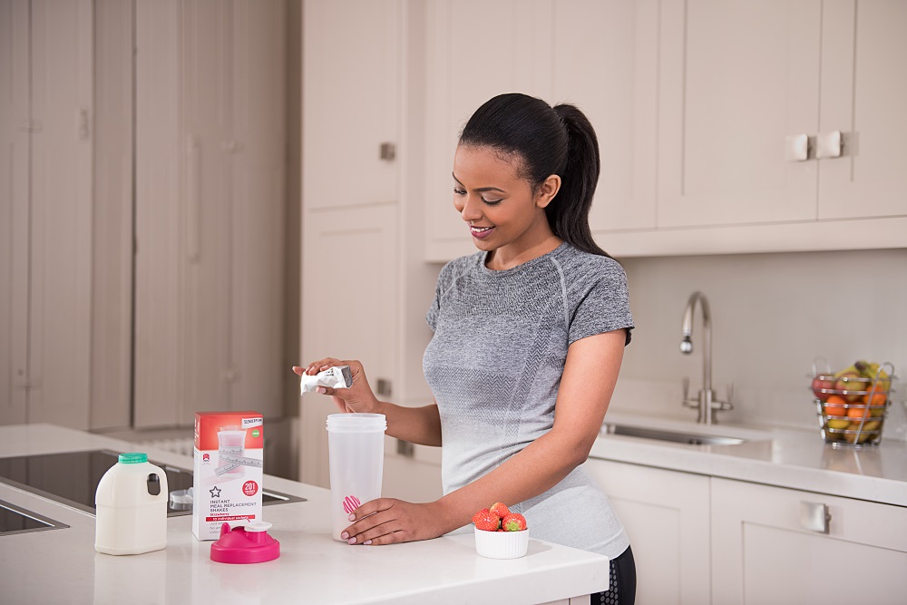 lady in kitchen mixing a protein shake