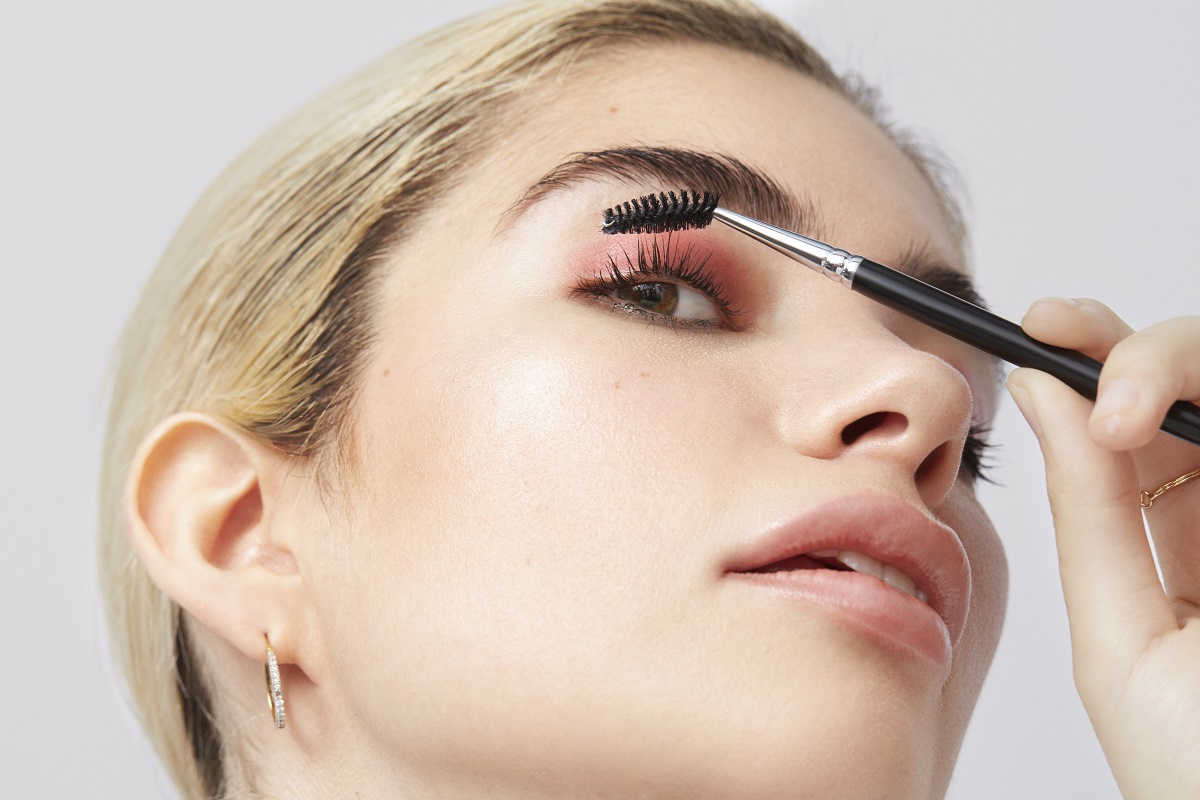 Younge female holding a spoolie to her eye lashes