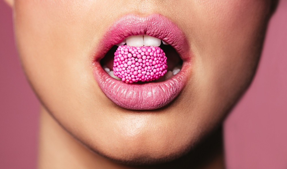 Close up of pink lips eating a pink sweet