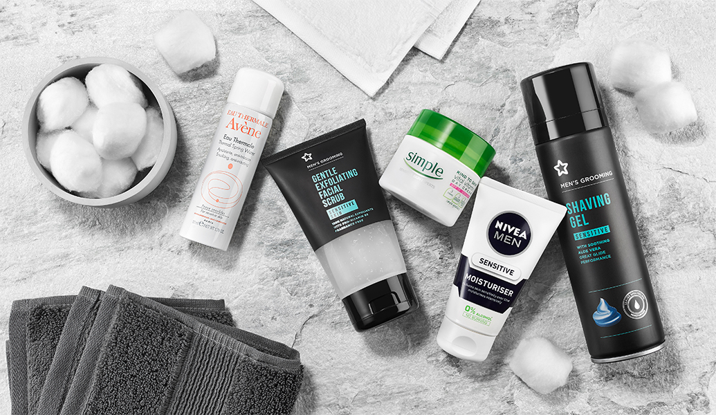 sensitive skincare products for men alongside cotton wool and flannels on a marble background