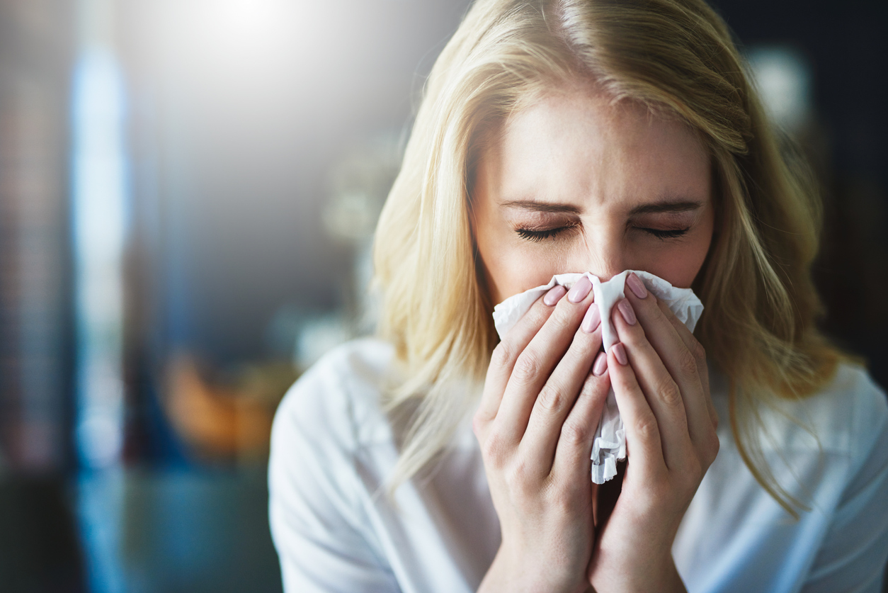 Blonde female blowing her nose