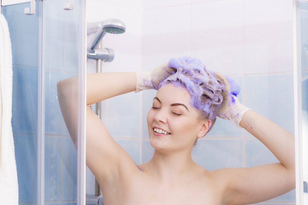 Women applying purple shampoo to coloured hair for what is hair toner article