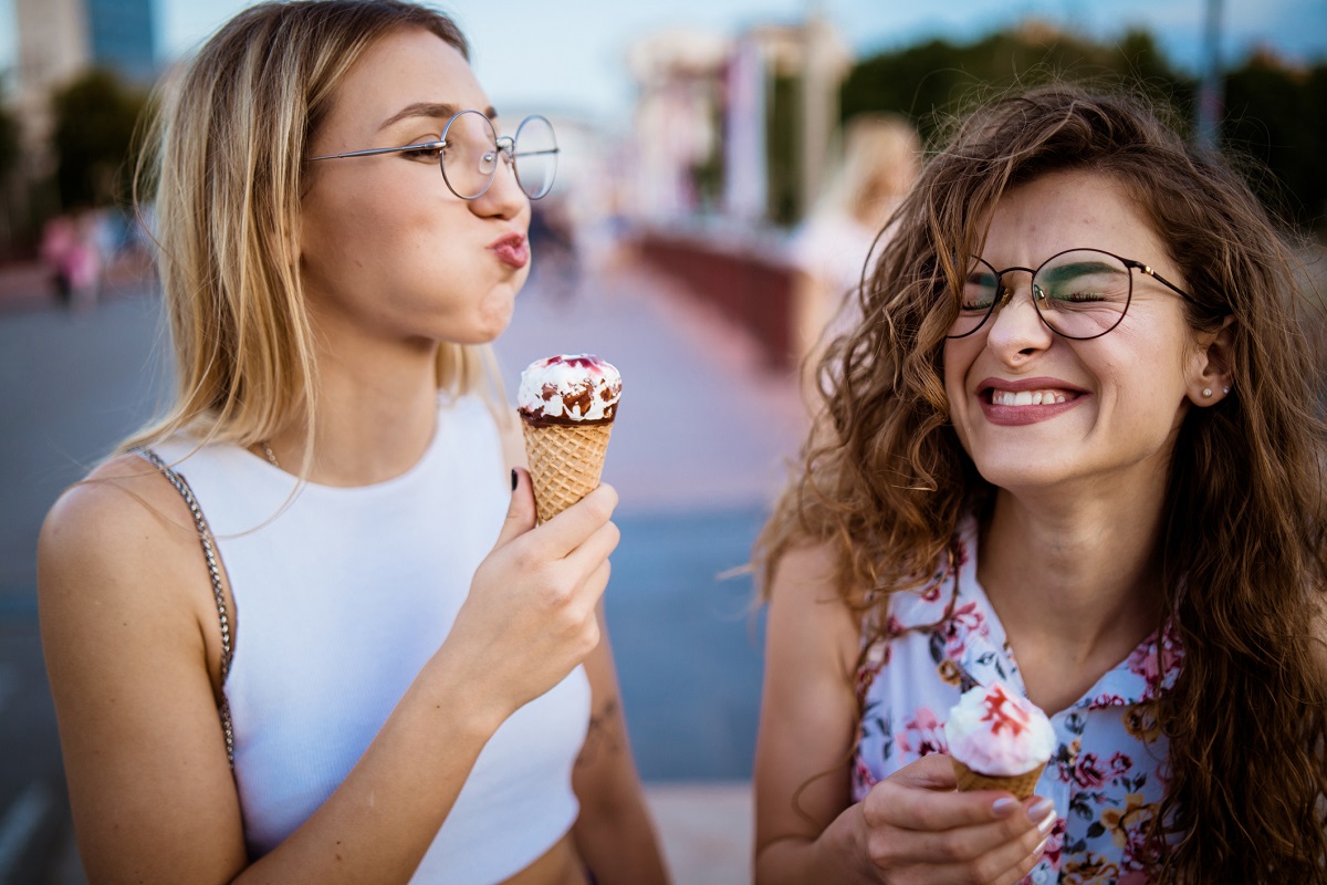 Two females eating ice cream and wearing glasses on a sunny day