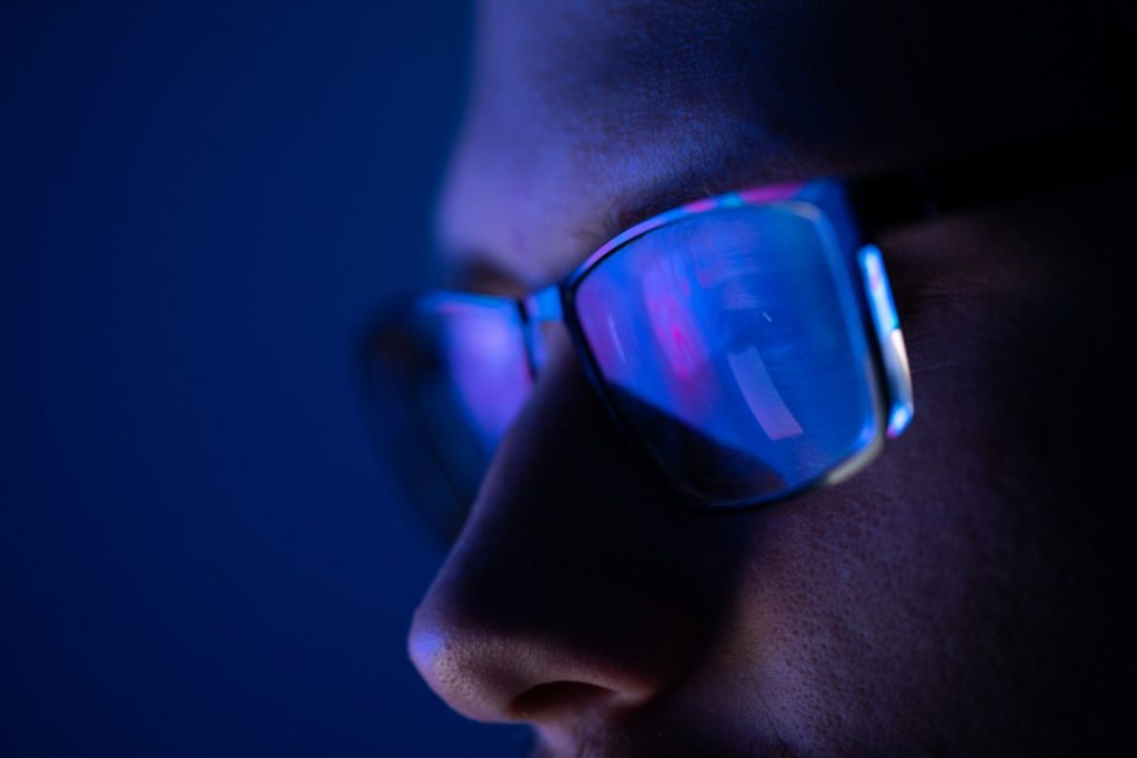 Blue light reflected on close up of male face with glasses