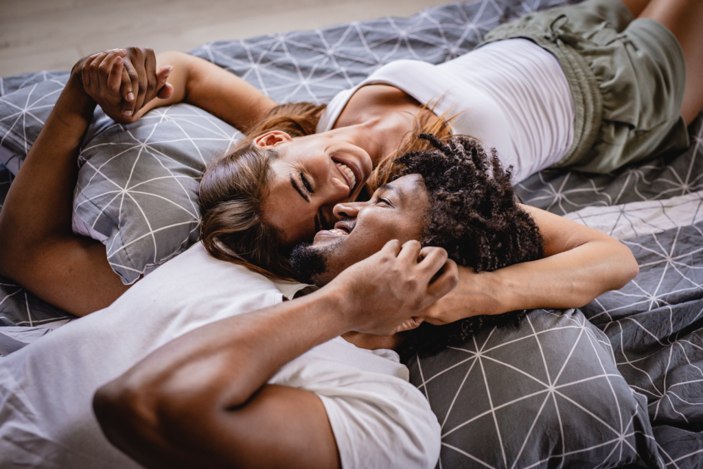 Playful young couple laying on bed