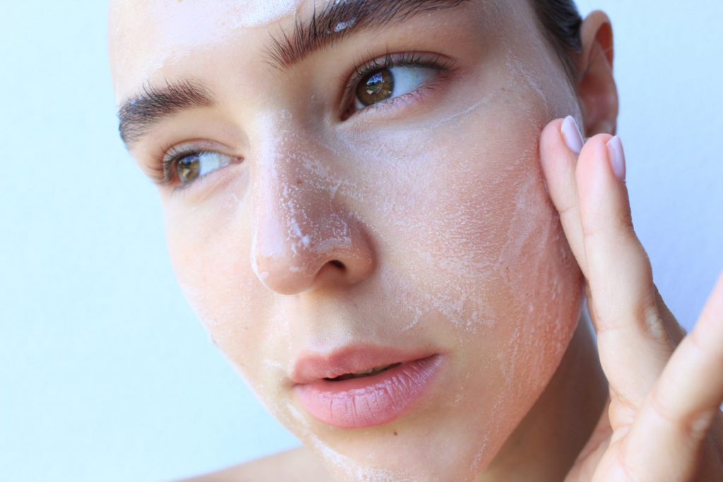 Woman applying cleansing foam to her face