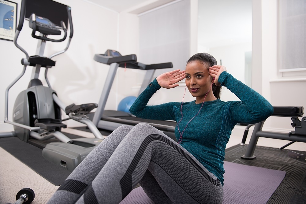 Young women doing sit ups in the gym with headphones in