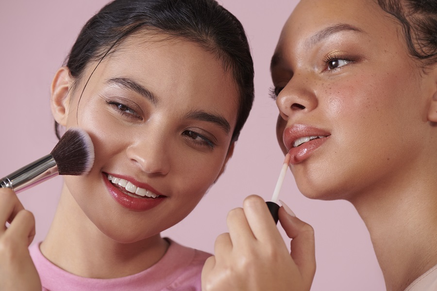 two women applying lip gloss and blusher. 