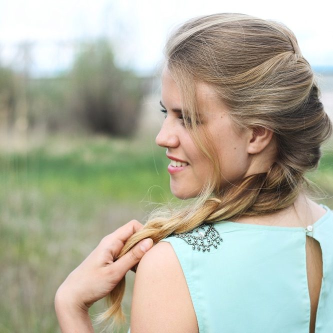 young beautiful blond girl smiling and  holding in hand natural hair in braid outdoor spring summer day