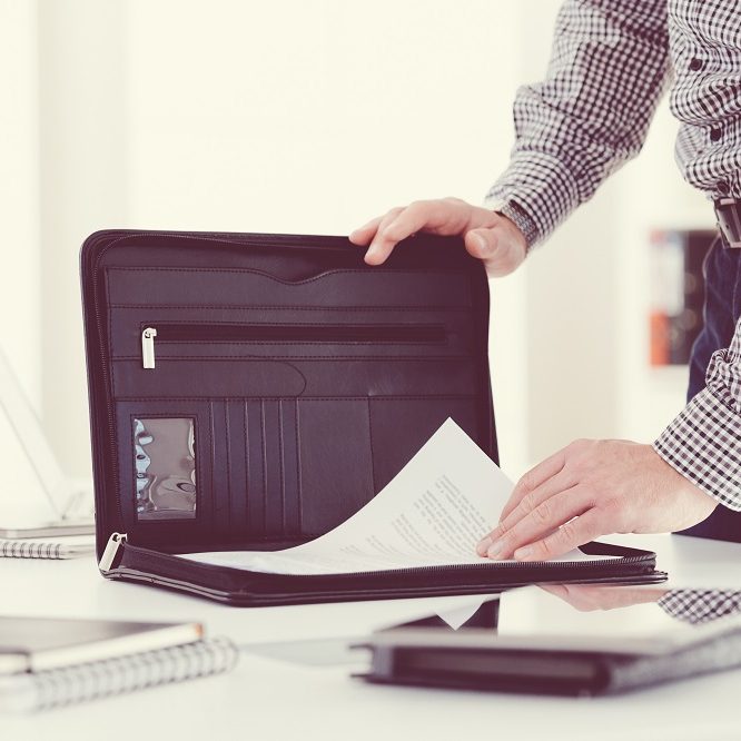 Man taking documents from briefcase in an office. Close up of hands, unrecognizable person.